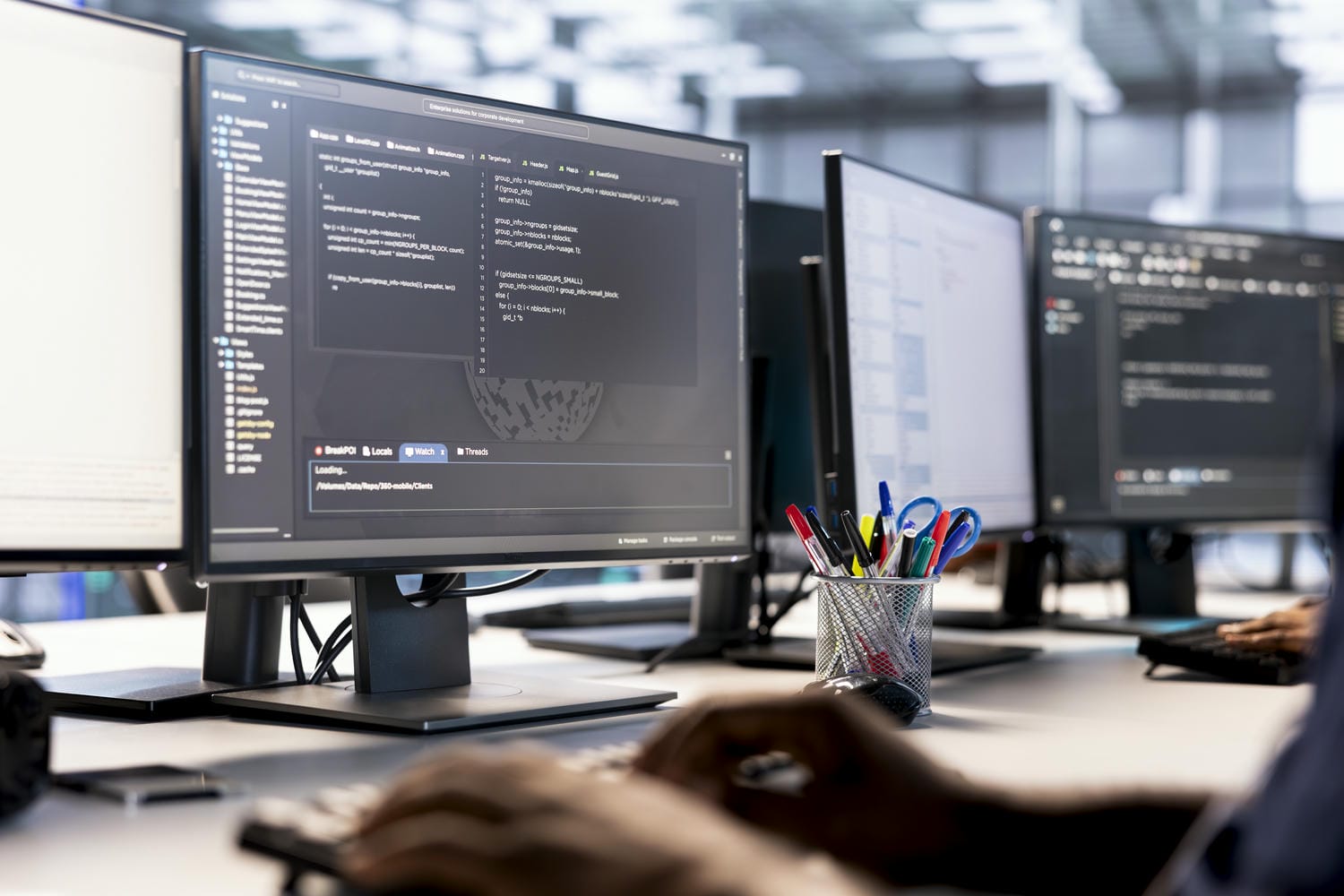 Developer working on multiple monitors with code editors open, representing a professional software development environment